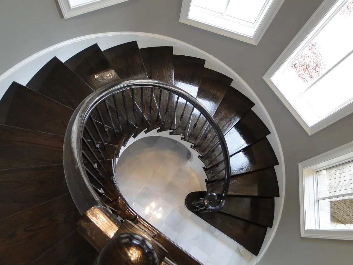 A custom circular staircase with a sweeping hardwood handrail
